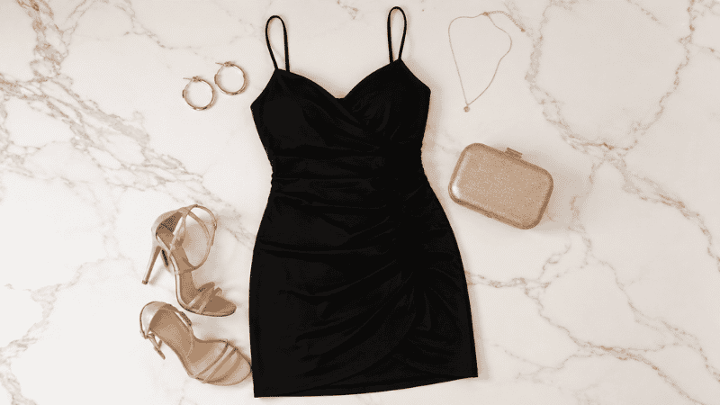 Black homecoming dress styled with gold jewelry, nude heels, and a small metallic clutch