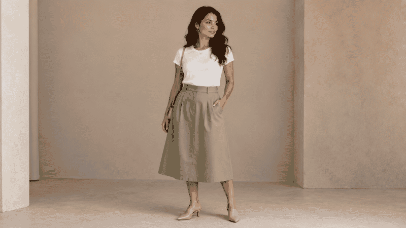 Petite woman in a brunch outfit wearing a high-waist midi skirt, fitted white tee, and mule sandals