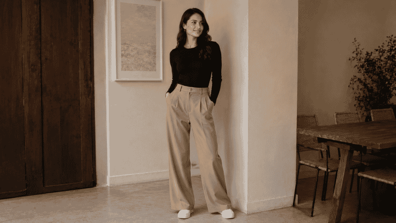 Woman in a movie date outfit wearing wide-leg trousers, fitted knit top, and clean white sneakers