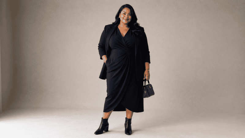 Curvy woman in a flattering work outfit wearing a navy wrap dress and structured blazer