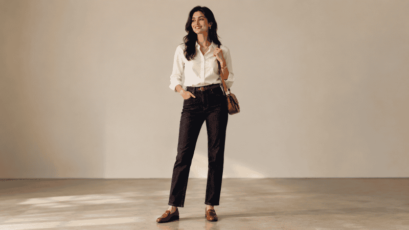 Tall woman in dark wash full-length straight-leg jeans with a tucked white blouse and flat loafers showing elegant proportions