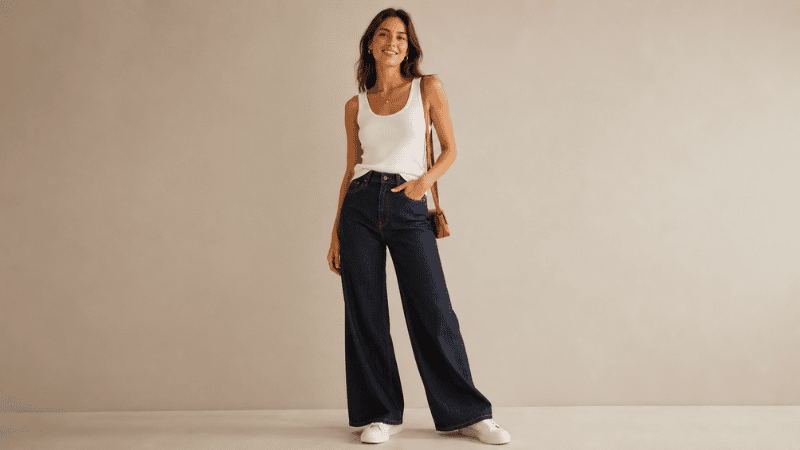 Woman in a chic wide leg pants outfit with a fitted white tank tucked in and white leather sneakers looking effortlessly stylish